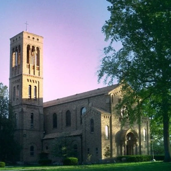Historic church with tall bell tower in warm evening light against a pastel sky, surrounded by trees; floral pattern overlays bottom left corner.
